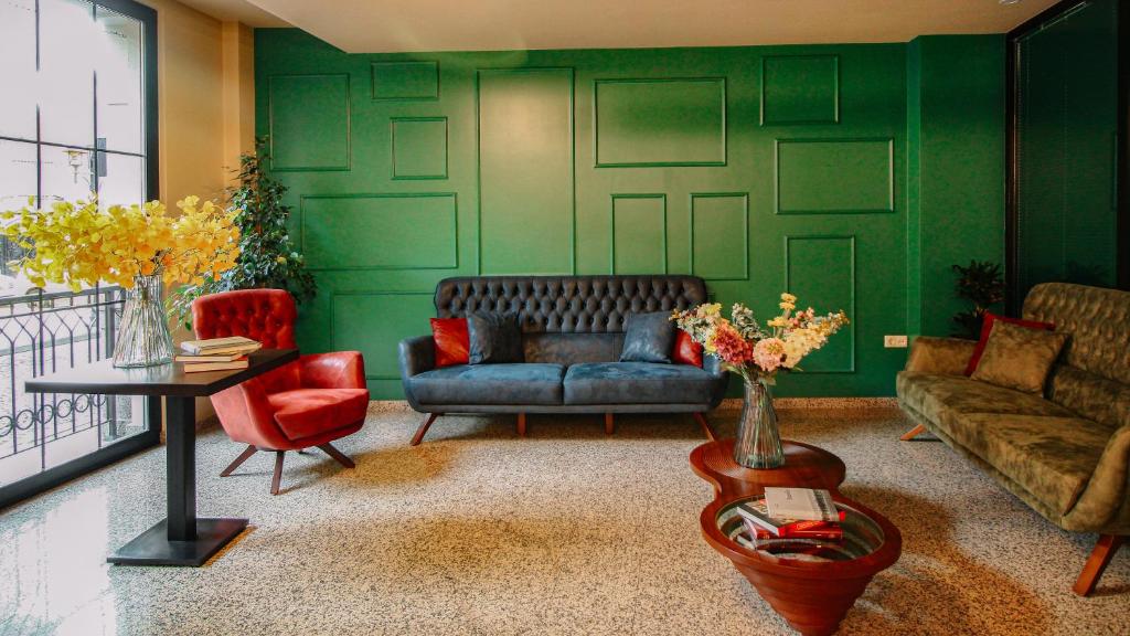 a living room with green walls and a couch and chairs at Hotel BLOOM Batumi in Batumi