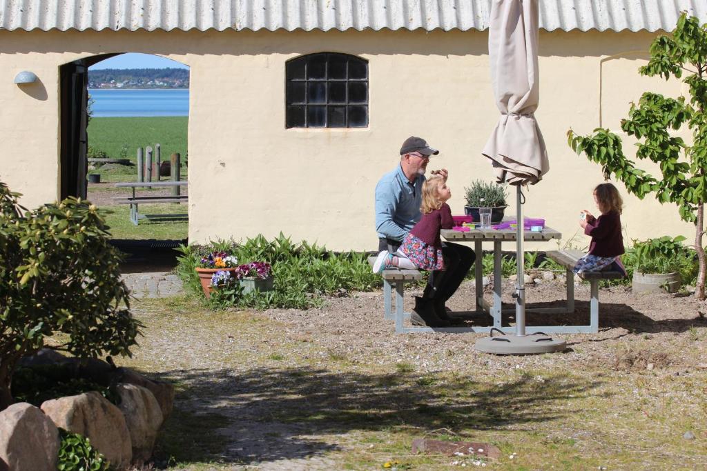 Ein Mann und zwei Kinder sitzen an einem Tisch. in der Unterkunft Stutteri Ahl near beach and town in Ebeltoft