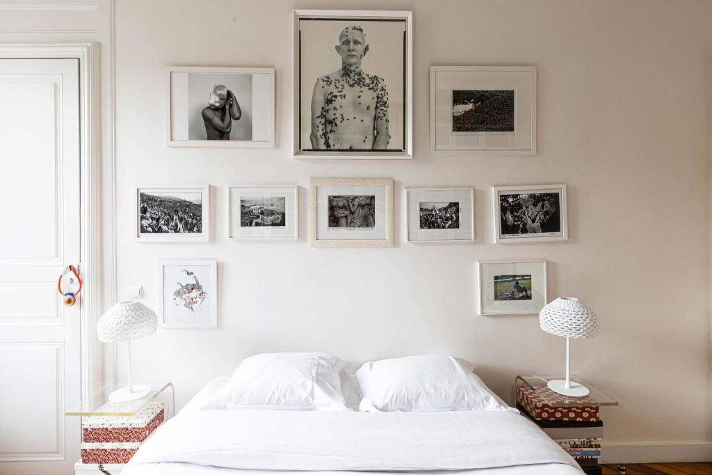 una camera da letto con un letto bianco e quadri appesi al muro di Veeve - La Fayette Light a Parigi