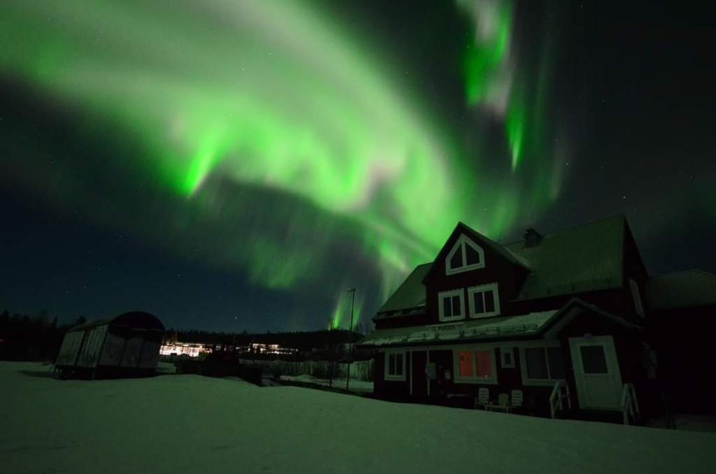 une maison et une maison avec l'aurore boréale dans le ciel dans l'établissement Arctic Colors Northern Lights Apartments, à Porjus