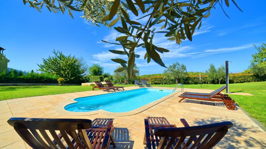 a swimming pool with three chairs and a table at Apartment Villa Mare2 with pool, sea view and hydromassage in Banjole