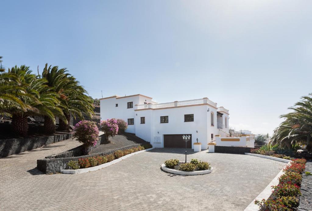 een wit huis met palmbomen en een oprit bij VILLA BELLAVISTA DE LOS VALLES in Teguise