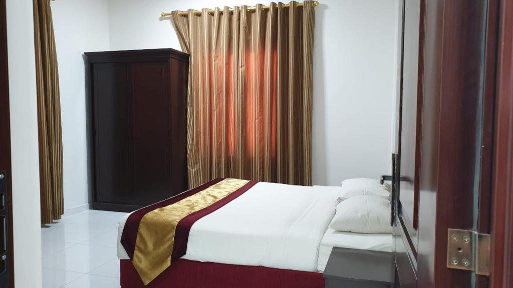 a bedroom with a bed and a curtain at Sea Hotel Apartment in Sur