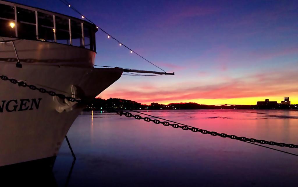 a boat docked in the water at sunset at Mälardrottningen Yacht Hotel in Stockholm