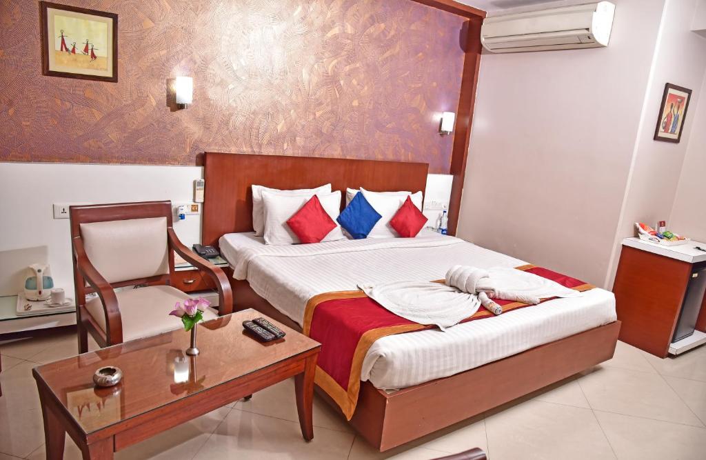 a bedroom with a bed with a chair and a table at Hotel Amit International in Bhilai