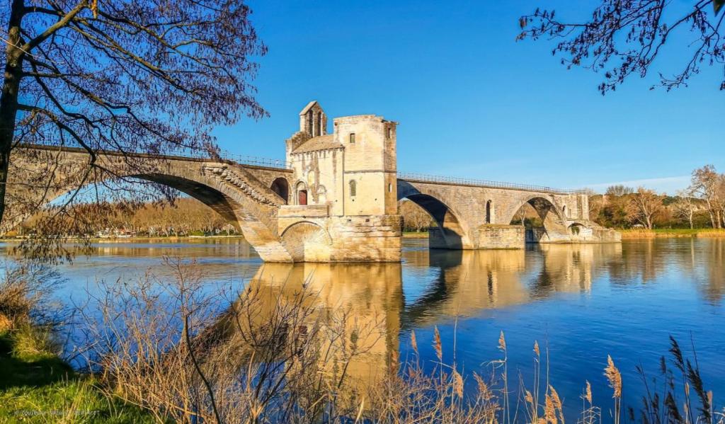 eine Brücke über einen Fluss mit einem Gebäude darauf in der Unterkunft Beausoleil in Avignon