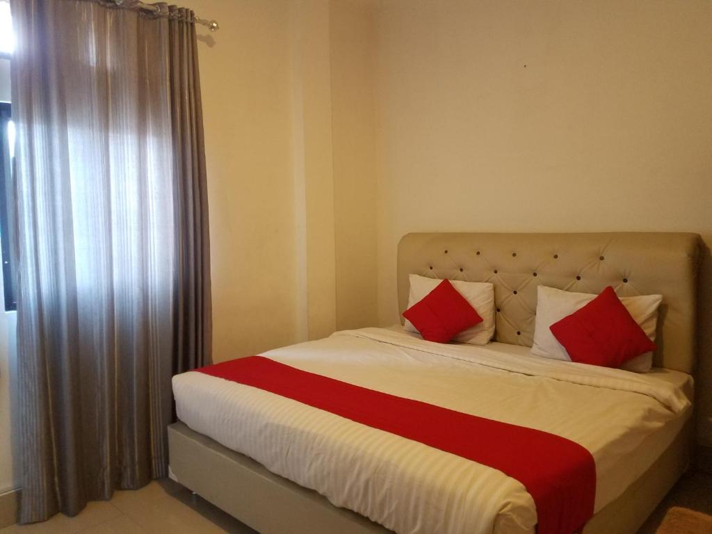 1 dormitorio con 1 cama con almohadas rojas y blancas en Mina Homestay Syariah, en Bukittinggi