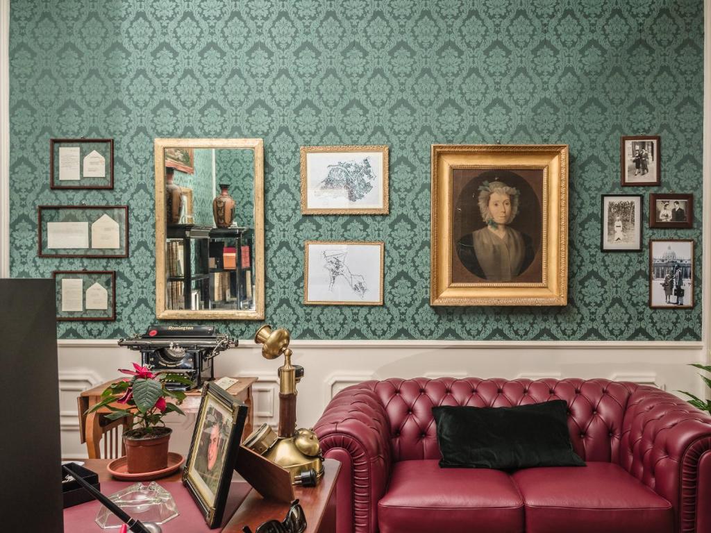 ein Wohnzimmer mit einem roten Sofa und gerahmten Bildern in der Unterkunft B&B Palazzo Policastri in Corigliano Calabro