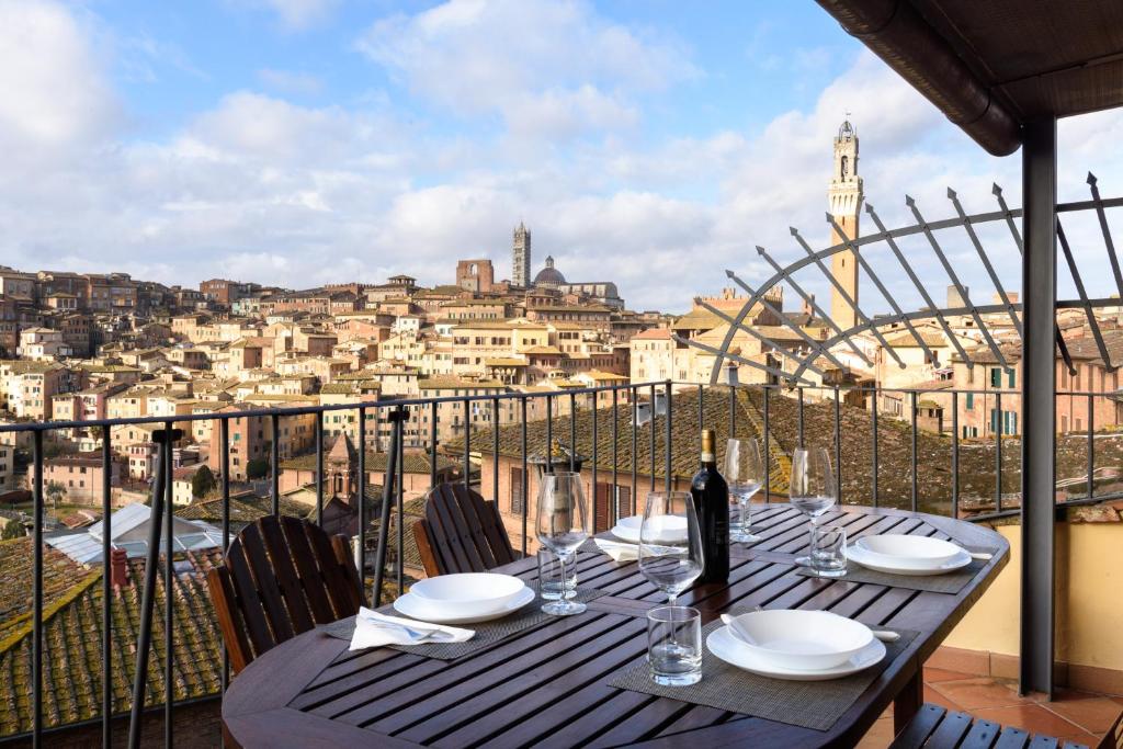 een tafel met glazen en een fles wijn op een balkon bij Appartamento panoramico San Martino 12 in Siena