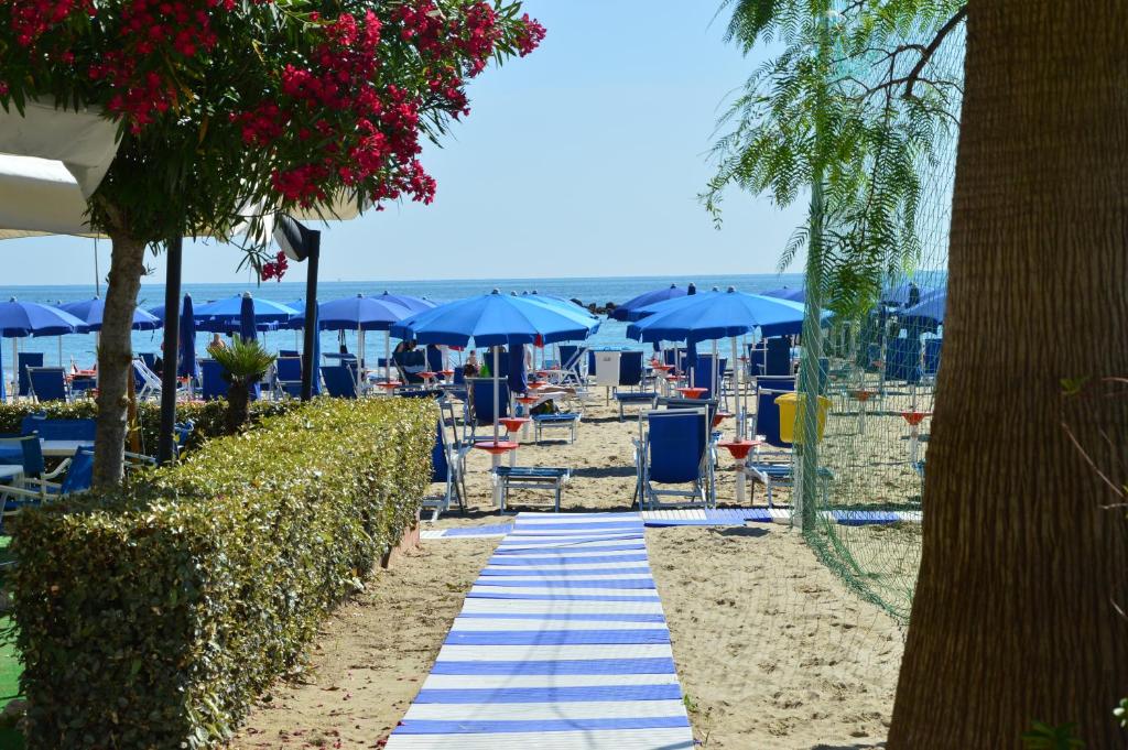 a beach with blue umbrellas and chairs on the sand at Mono Rosburgo 1 in Roseto degli Abruzzi