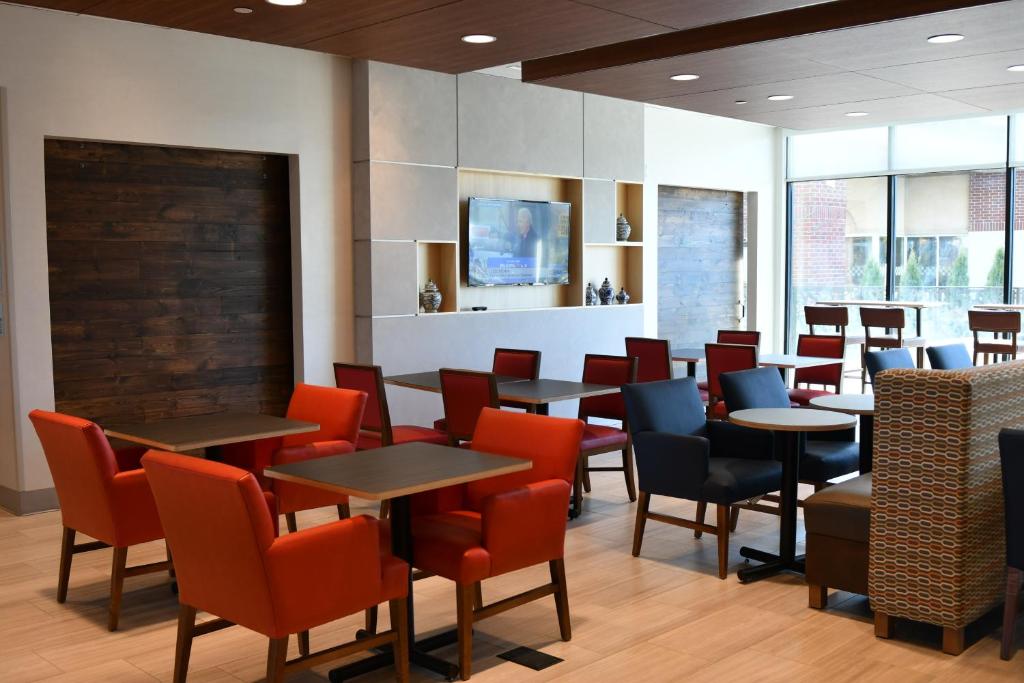 a dining room with tables and chairs and a tv at Holiday Inn Express & Suites - Romeoville - Joliet North, an IHG Hotel in Romeoville