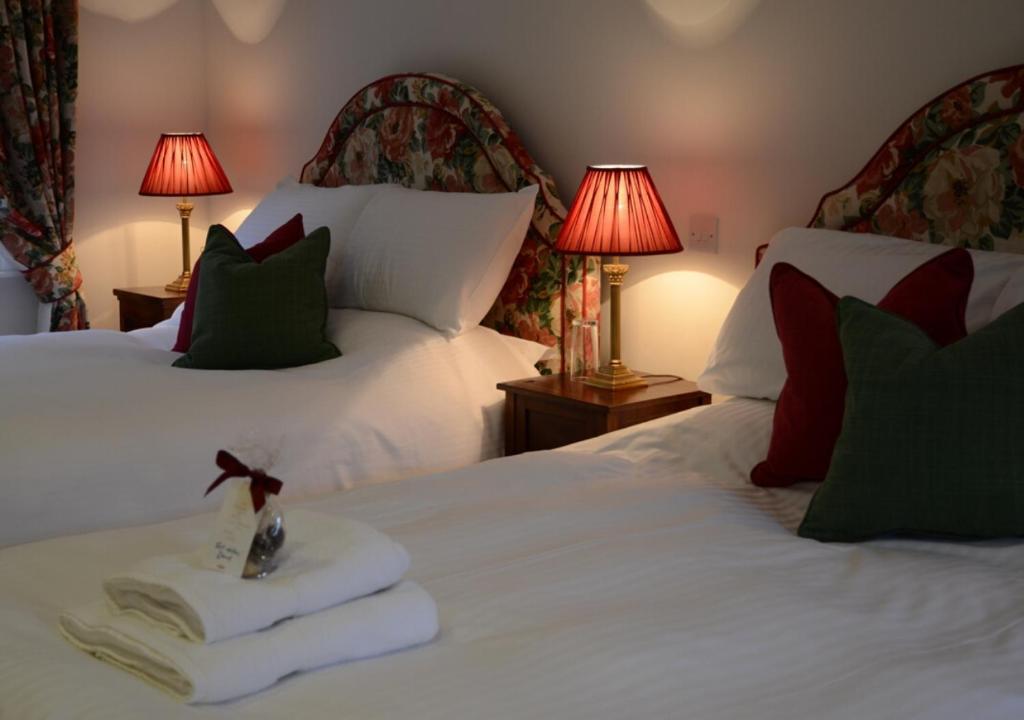 a bedroom with two beds with white sheets and green pillows at Delphi Lodge in Leenaun