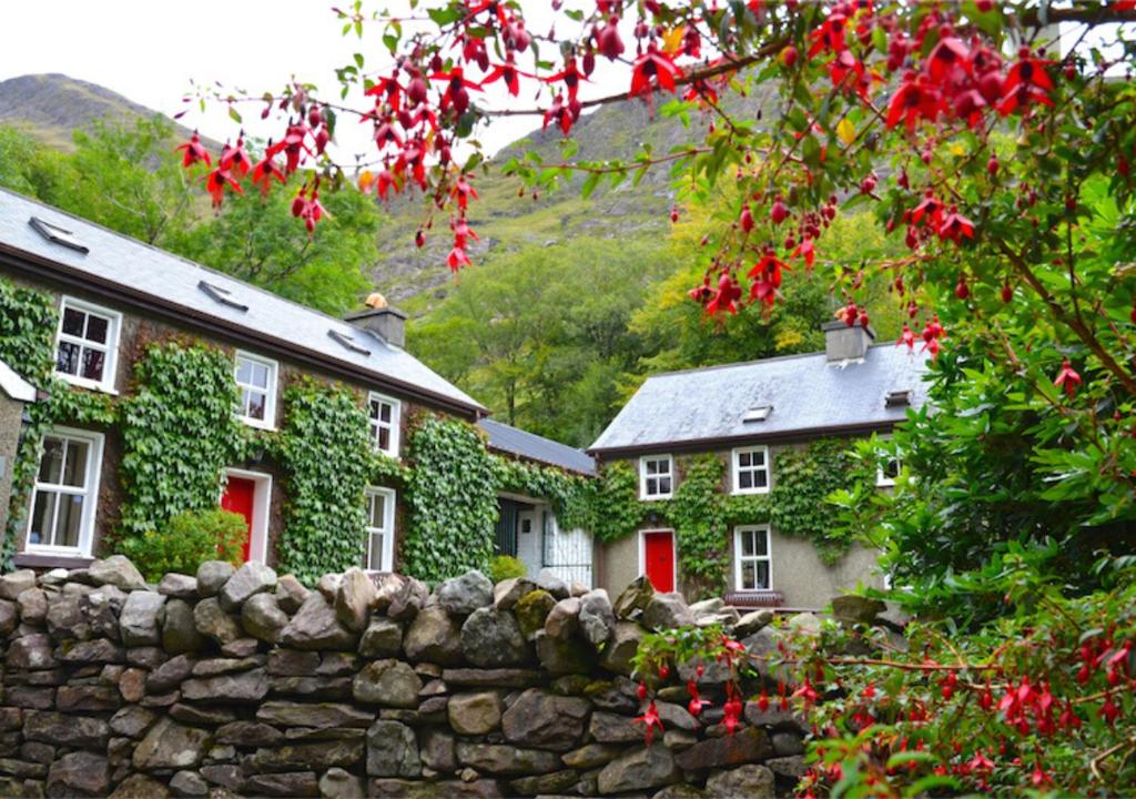 a stone fence in front of a house with red doors at Delphi Lodge in Leenaun