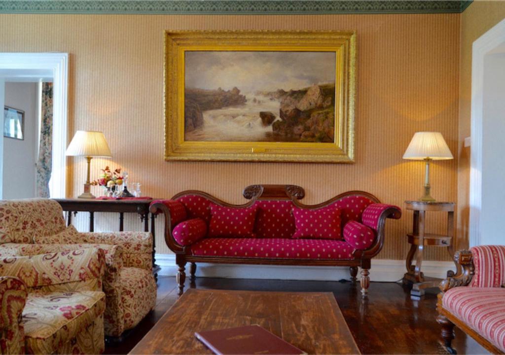 a living room with a red couch and a painting at Delphi Lodge in Leenaun