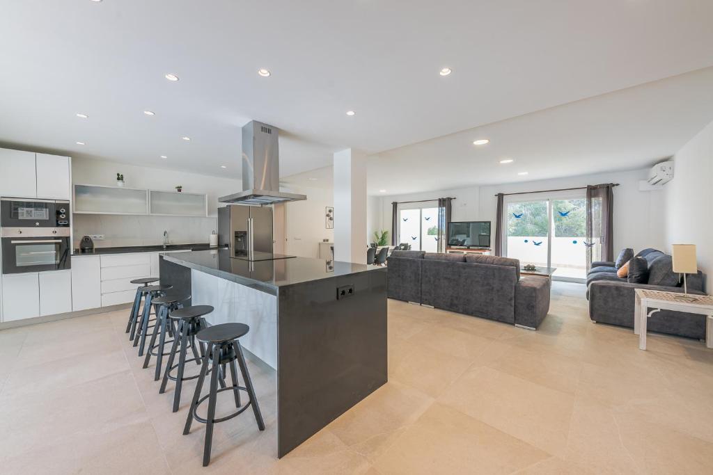 a kitchen and living room with a counter and stools at YupiHome Villa Bahía de Palma - Family Only in Cala Vinyes