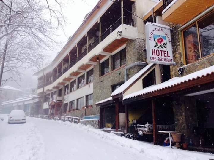 a snow covered street in front of a hotel at Mountain Rose Hotel & Restaurant in Pedoulas
