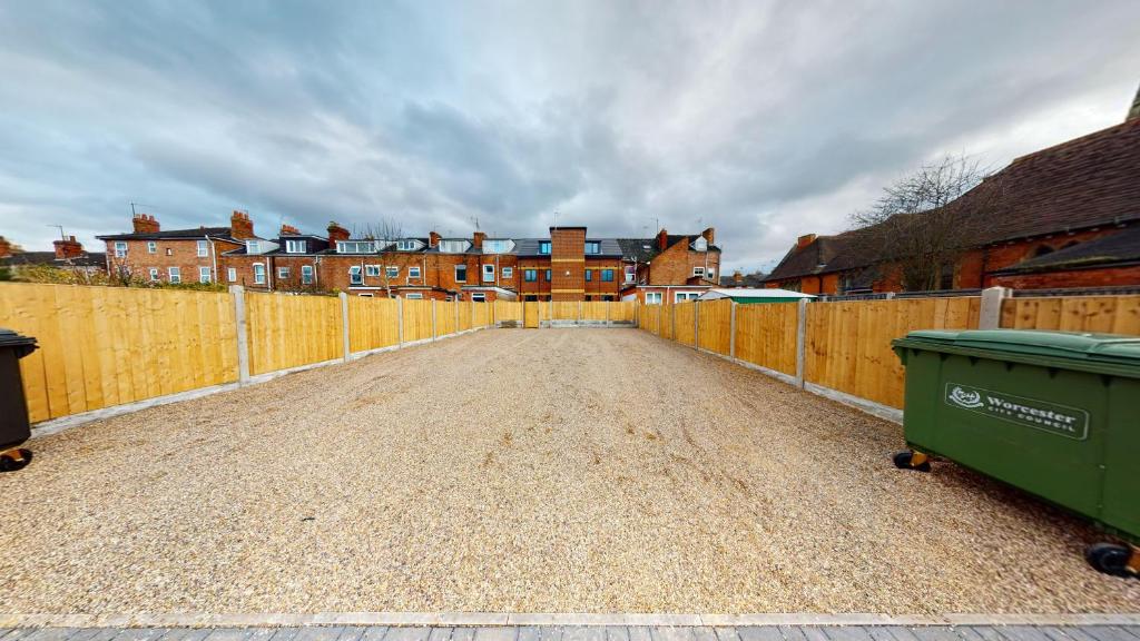 a fence with a dirt road in front of houses at City Lodge Serviced Apartments Worcester City Centre - Parking in Worcester