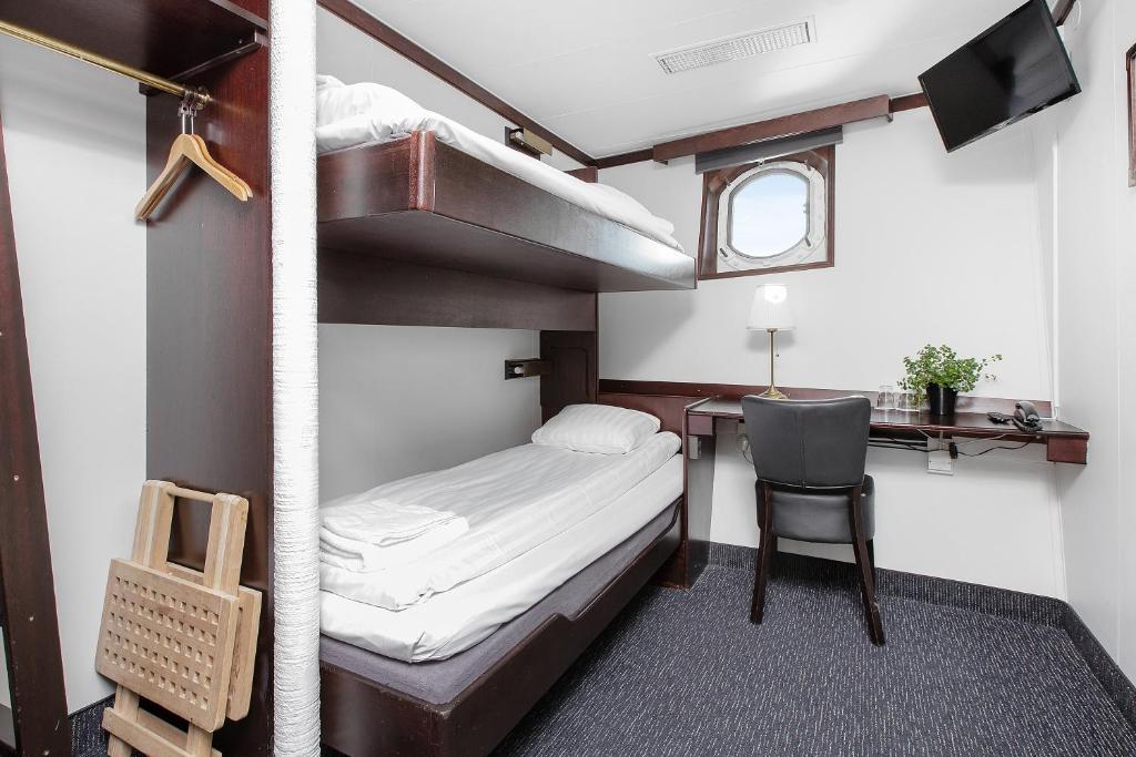 a bedroom with a bunk bed and a desk with a chair at Mälardrottningen Yacht Hotel in Stockholm