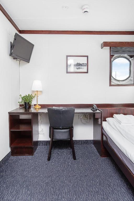 a bedroom with a desk and a bed and a chair at Mälardrottningen Yacht Hotel in Stockholm