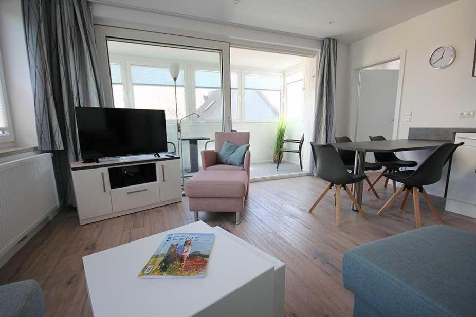 ein Wohnzimmer mit einem TV, einem Tisch und Stühlen in der Unterkunft Große Ferienwohnung 3 mit Meerblick und Strandkorb im Haus Seeluft Duhnen in Cuxhaven