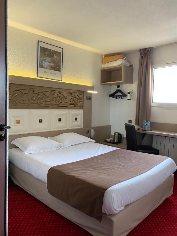 ein Hotelzimmer mit einem großen Bett und einem Schreibtisch in der Unterkunft Kimotel Epône-Flins in Épône