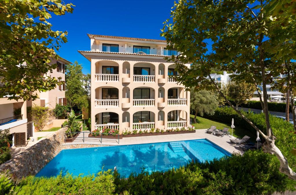 een groot huis met een zwembad ervoor bij Apartamentos S'Olivera in Canyamel