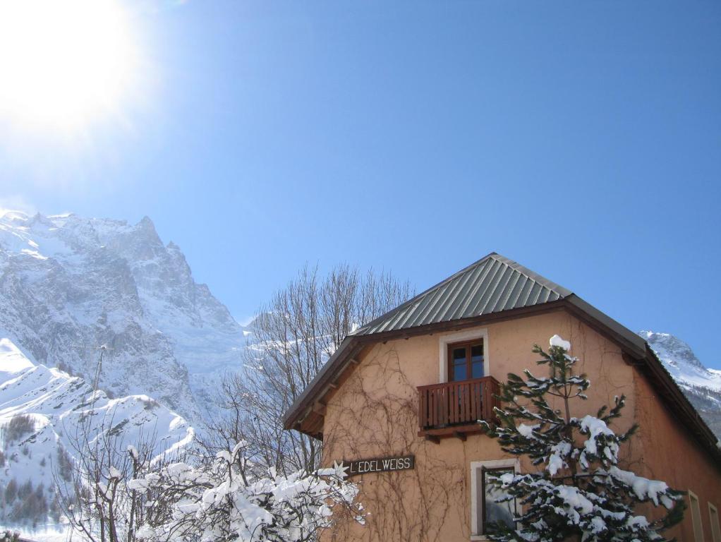 un edificio con balcón y montañas cubiertas de nieve en Hotel Auberge Edelweiss, en La Grave