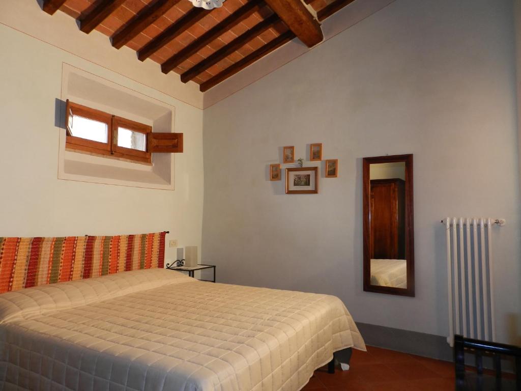 een slaapkamer met een bed en een spiegel bij Angolo Alla Fortezza - Gigliola Contucci in Montepulciano