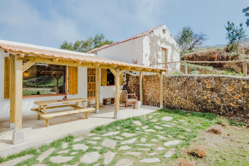 Ce cottage dispose d'une table de pique-nique et d'un mur en pierre. dans l'établissement El Pino Centenario 8, à La Orotava