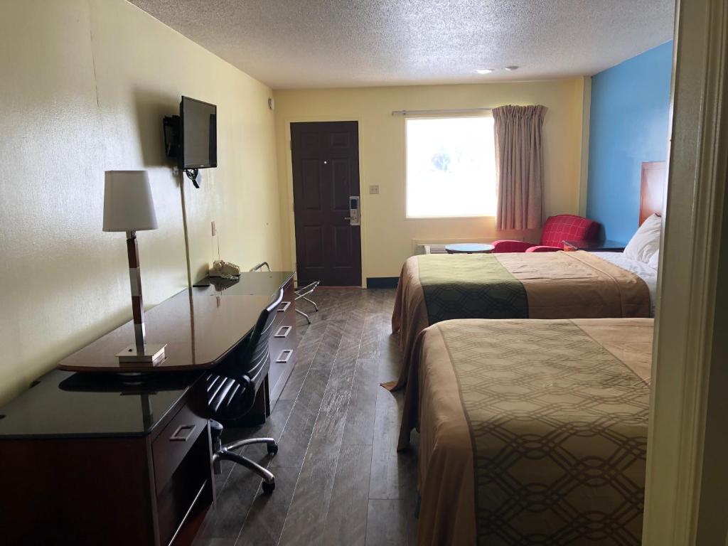 una camera d'albergo con due letti, una scrivania e una finestra di Western Inn South a Kearney