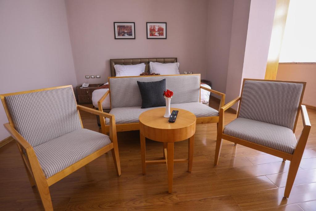 een woonkamer met 2 stoelen en een tafel en een bed bij New Day Hotel in Addis Ababa