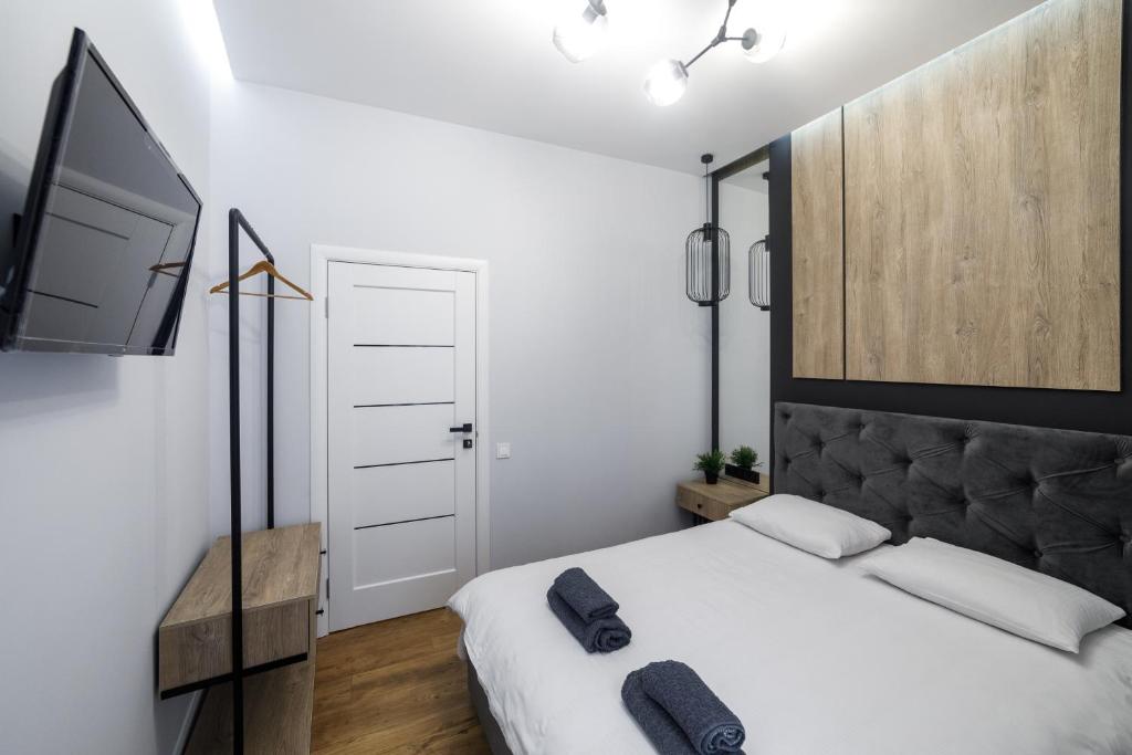 1 dormitorio con 1 cama blanca y TV en Royal apartment on Hmelnytskogo 37, en Leópolis