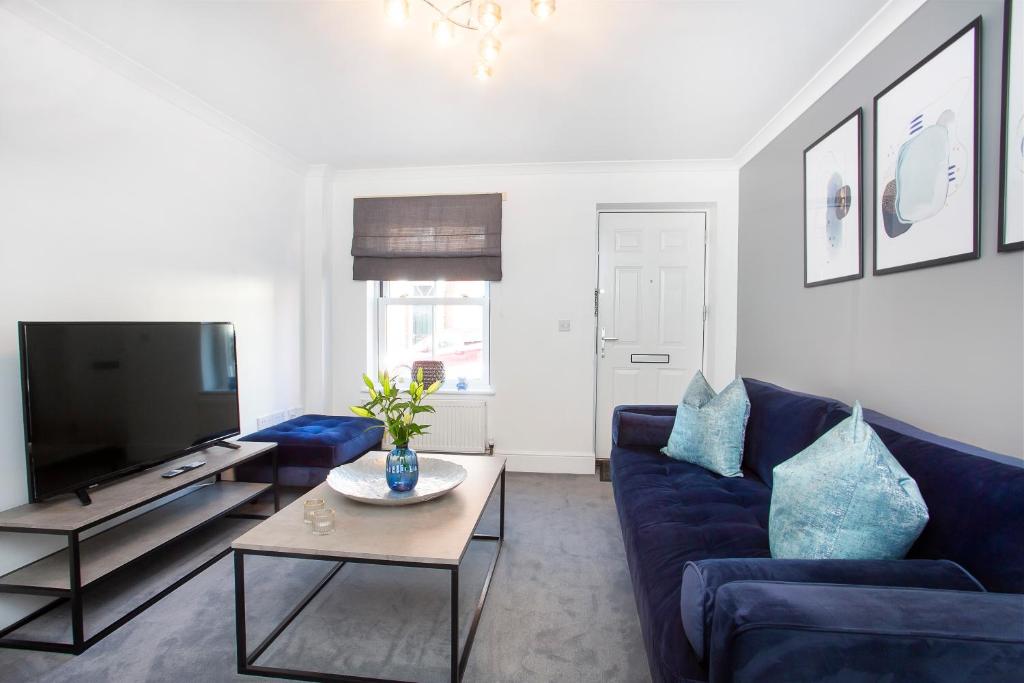 a living room with a blue couch and a tv at Knavesmire Mews 3 bedrooms-Free parking in York