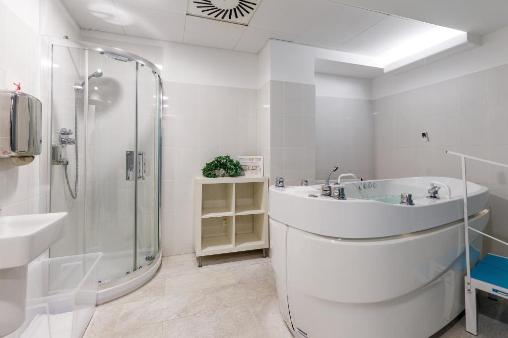 a white bathroom with a shower and a sink at Hotel Thermal in Karlovy Vary