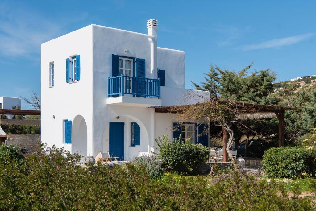 Casa blanca con ventanas azules y balcón. en Villa Emerald, en Isterni
