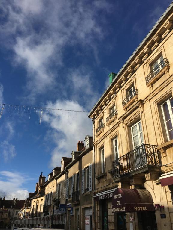 a row of buildings on a street with a blue sky at Hôtel du Commerce in Semur-en-Auxois