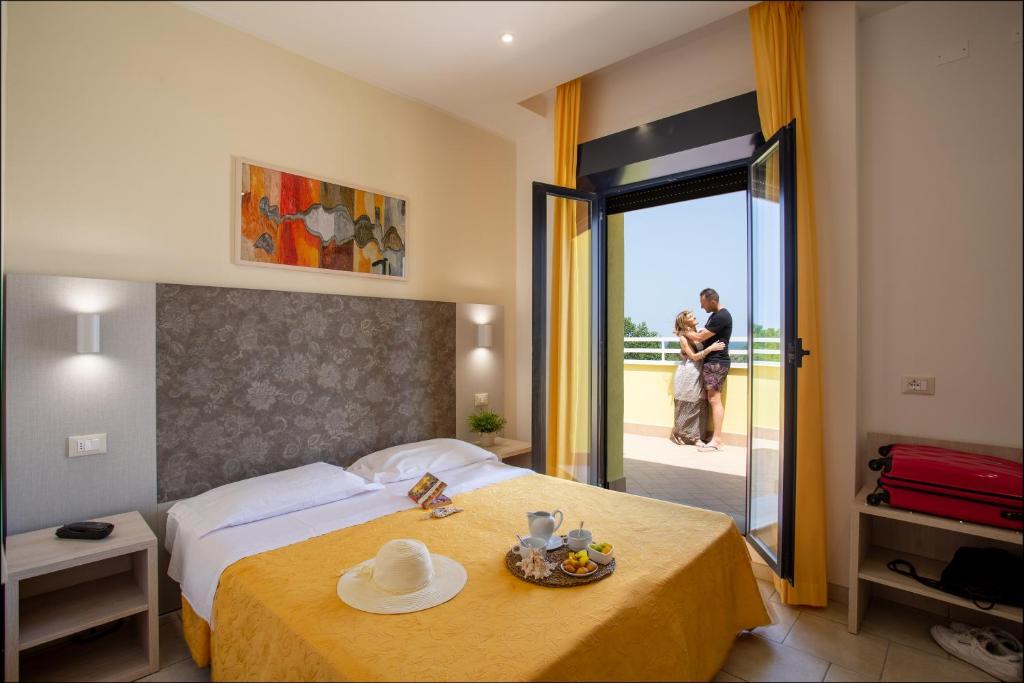 a hotel room with a bed and a couple standing outside at Hotel Reyt in Rimini