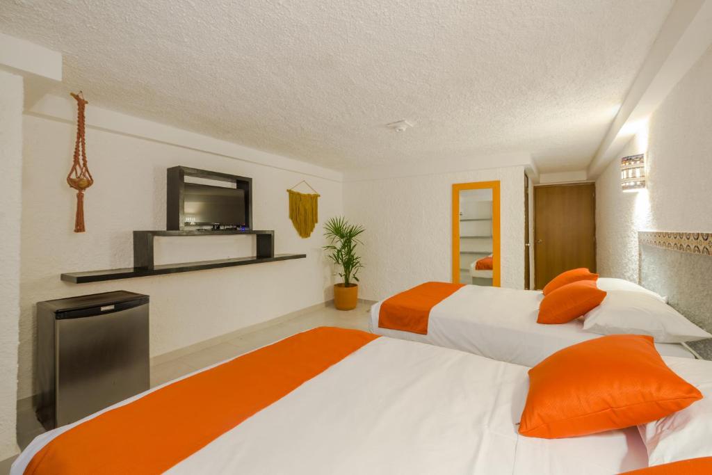 two beds in a room with orange and white at Hotel Puerto Caracol in Puerto Morelos