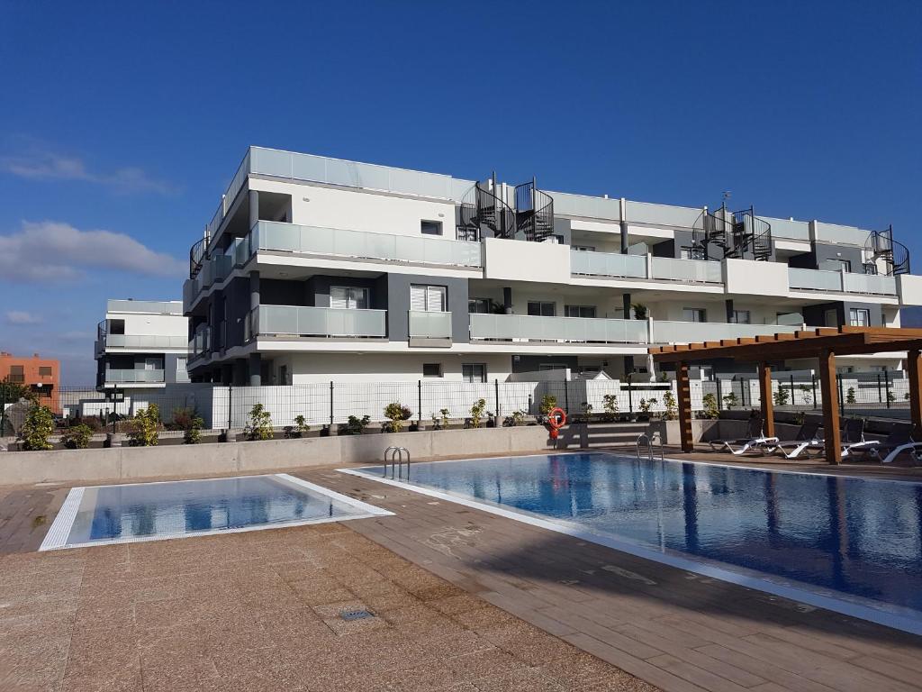 Penthouse Apartment Tejita Beach في La Tejita: مبنى فيه مسبح امام مبنى