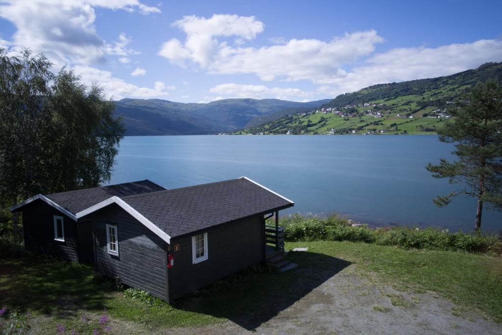 ein kleines Haus neben einem großen Wasserkörper in der Unterkunft Lyngmo Hytter in Hafslo