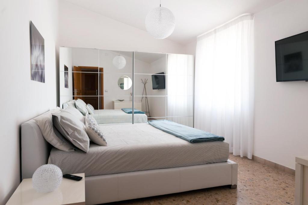 a white bedroom with a bed and a mirror at Fly by Suites Pescara in Pescara