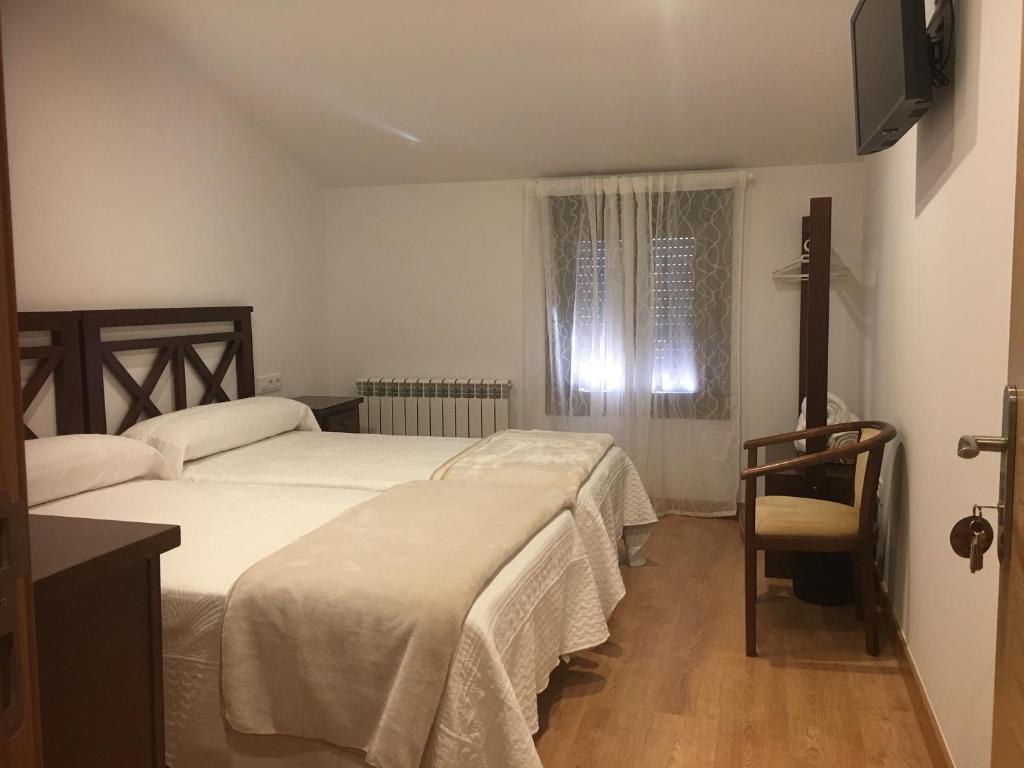 a bedroom with two beds and a window and a chair at La Casa del Hilario in Milagro