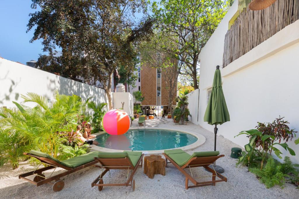 a pool with chairs and a beach ball and an umbrella at oOstel Smart Hostel - Tulum Pueblo in Tulum