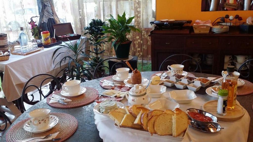 uma mesa com pão, chávenas e pratos de comida em El Perlindango em Villademar