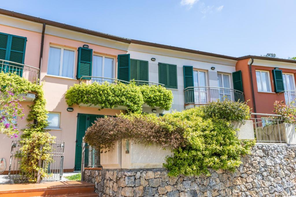 a building with green shutters and a stone wall at Baia Blu RTA Residence in Lerici
