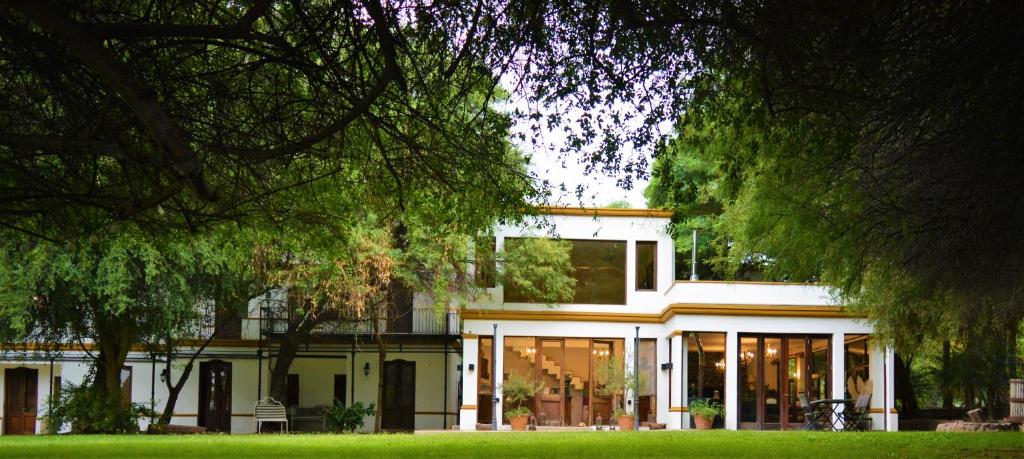 a large white house with glass doors and trees at Posada del Olivo in Nonogasta