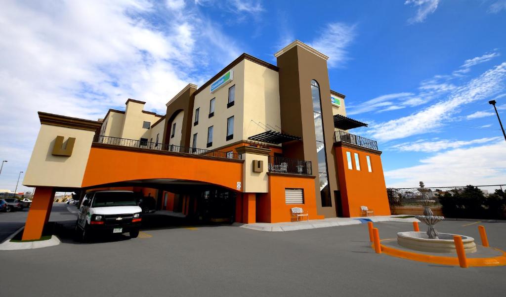 a building with a car parked in a parking lot at Hotel Consulado Inn in Ciudad Juárez