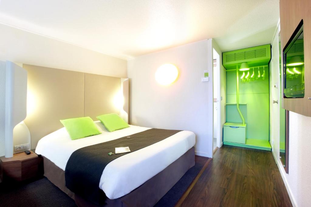 サント・リュース・シュル・ロワールにあるHôtel Inn Design Resto Novo Nantes Sainte Luceの緑をアクセントにした大型ベッドが備わるホテルルームです。