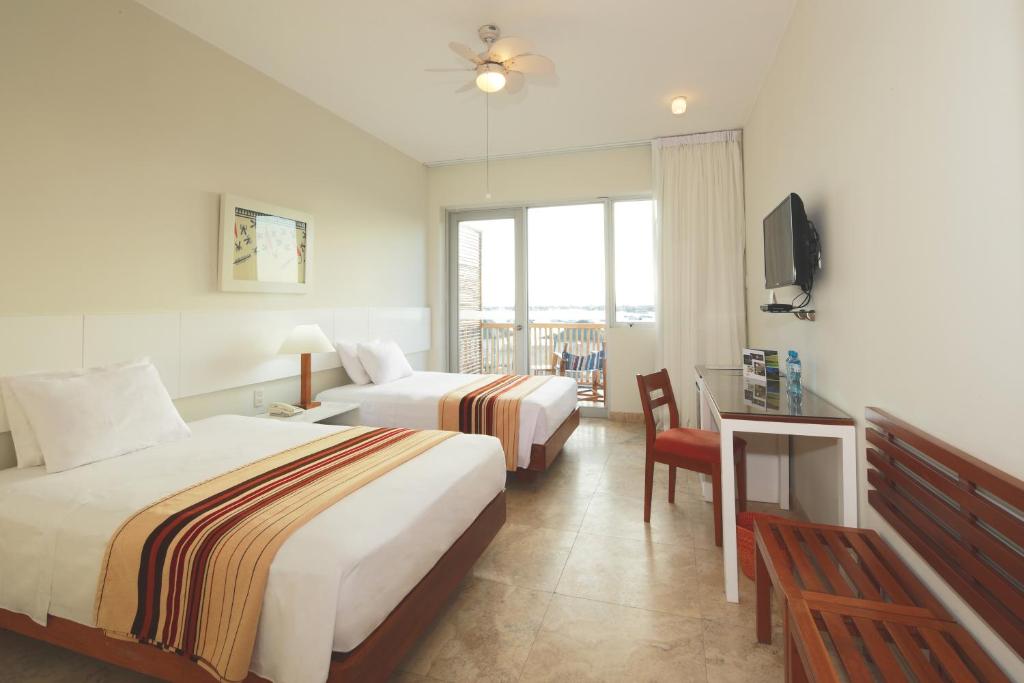 Una habitación de hotel con dos camas y un televisor. en San Agustin Paracas, en Paracas