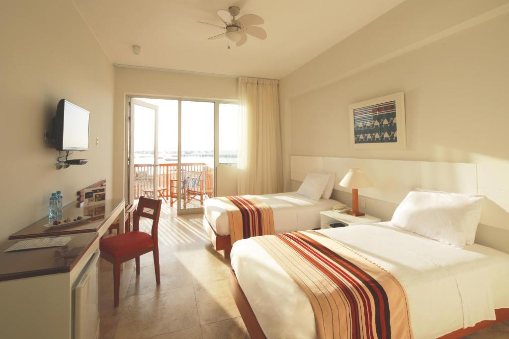 Una habitación de hotel con dos camas y un escritorio. en San Agustin Paracas, en Paracas